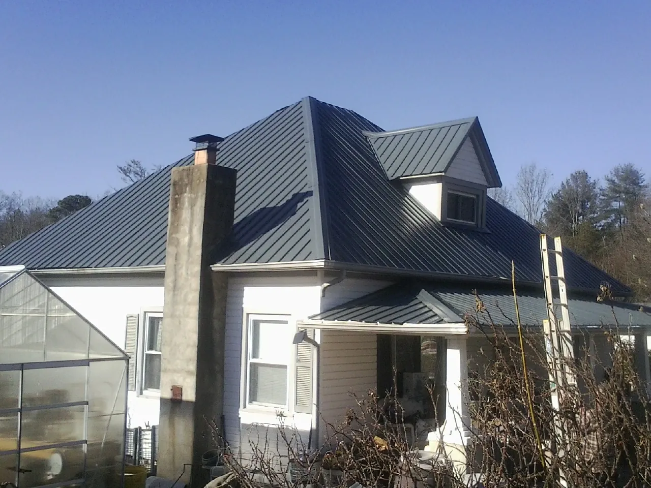 Dark blue standing seam metal roof on a white farmhouse with dormer — Slate & Tile Roof Repair by Roofing Brothers in Damascus
