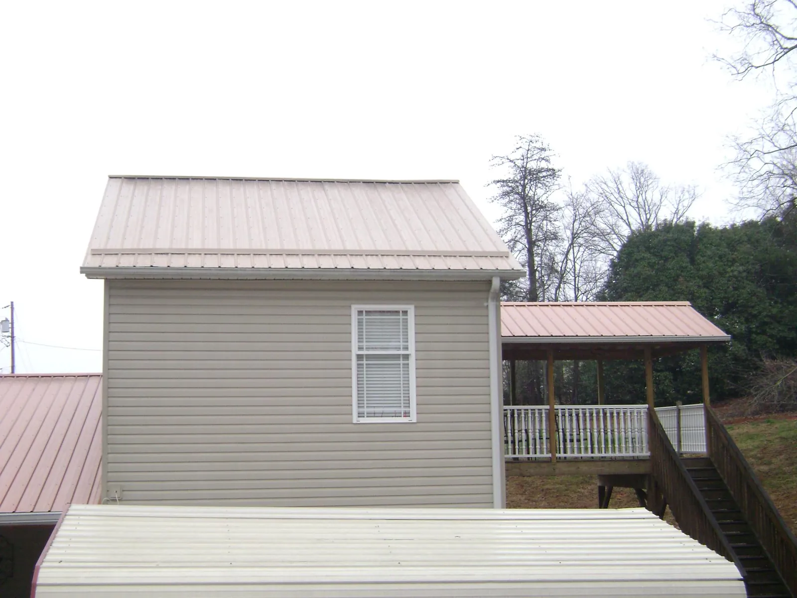 Tan metal roofs on a two story addition and attached porch, from a Roof Replacement job in Damascus